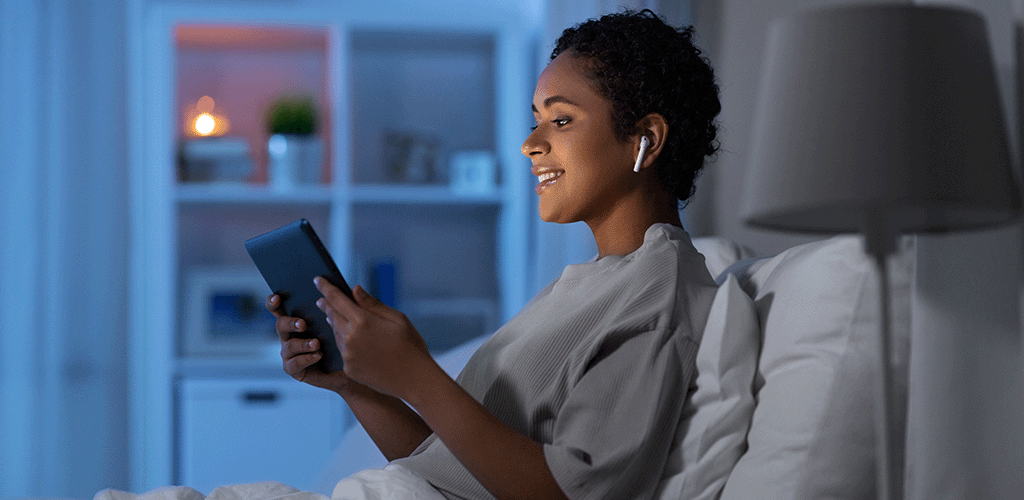 Woman in bed streaming music through her ipad using wi-fi and broadband from Jurassic Fibre.