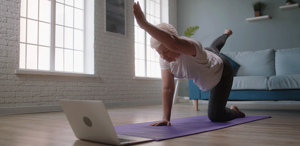 Woman doing online exercise class at home using Jurassic Fibre broadband