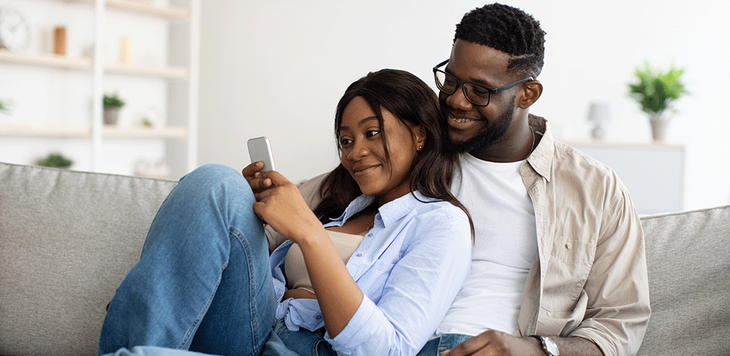 Couple sat on sofa looking at a mobile on 5G
